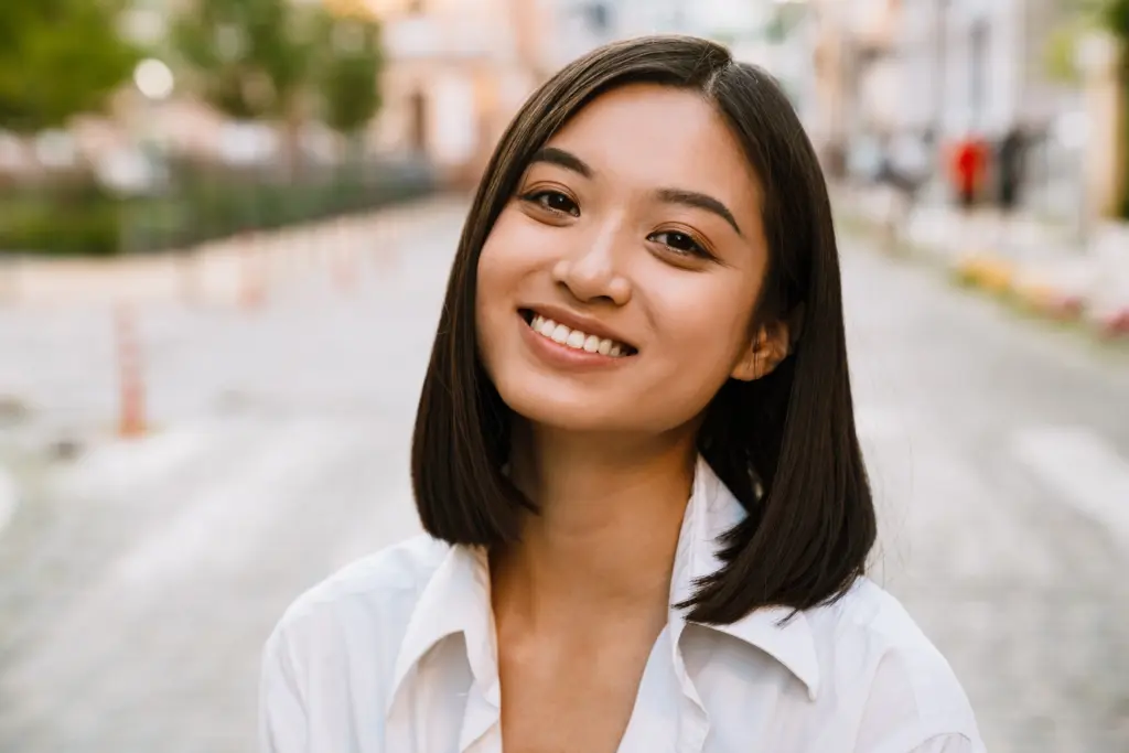 Confident woman smiling brightly outdoors, showcasing the natural-looking results from Dental Implants of Knoxville treatment.